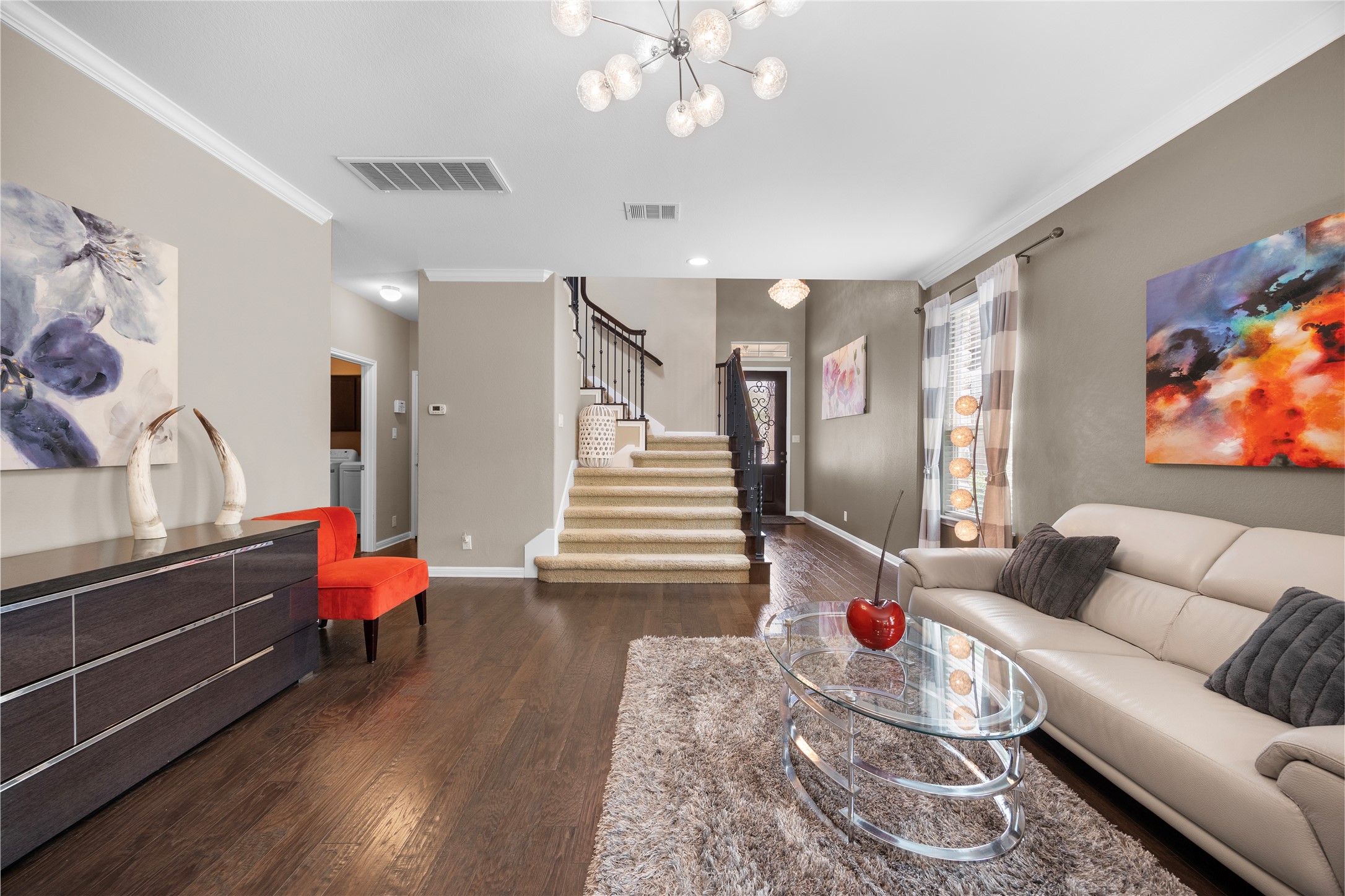 7308 Bandera Ranch Trail, Unit A Austin, TX 78750 - Photo 6 of 27 Living area featuring hardwood flooring, a modern chandelier, and a carpeted staircase with a dark wood banister