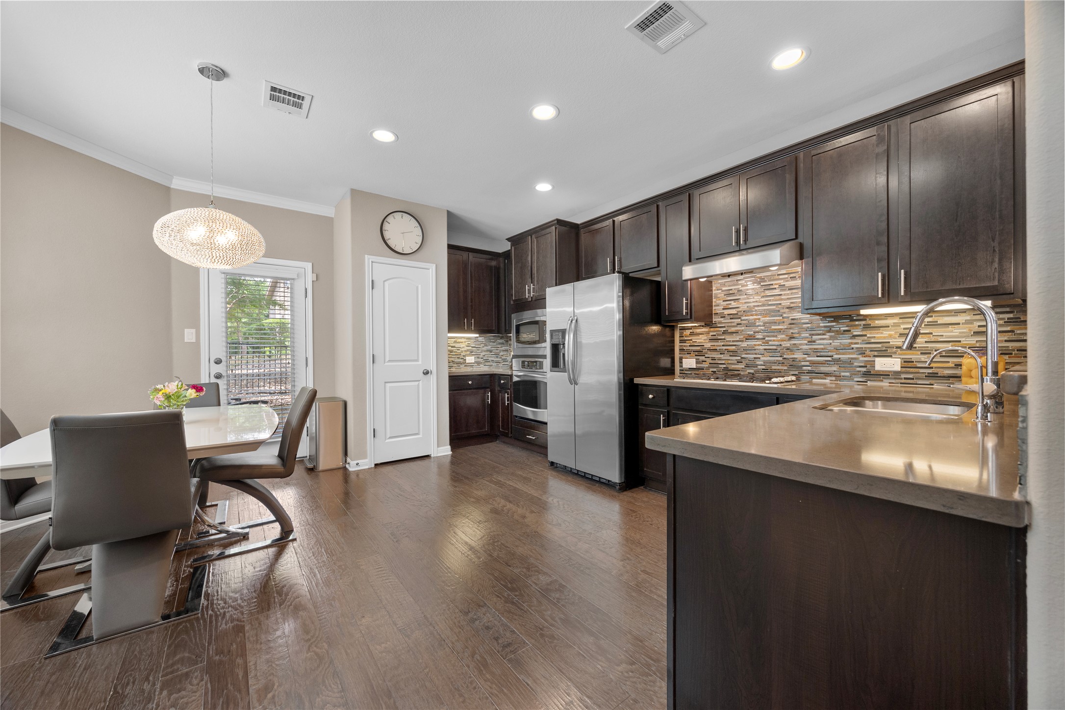 7308 Bandera Ranch Trail, Unit A Austin, TX 78750 - Photo 7 of 27 The property features a kitchen with dark cabinetry, stainless steel appliances, and a tiled backsplash