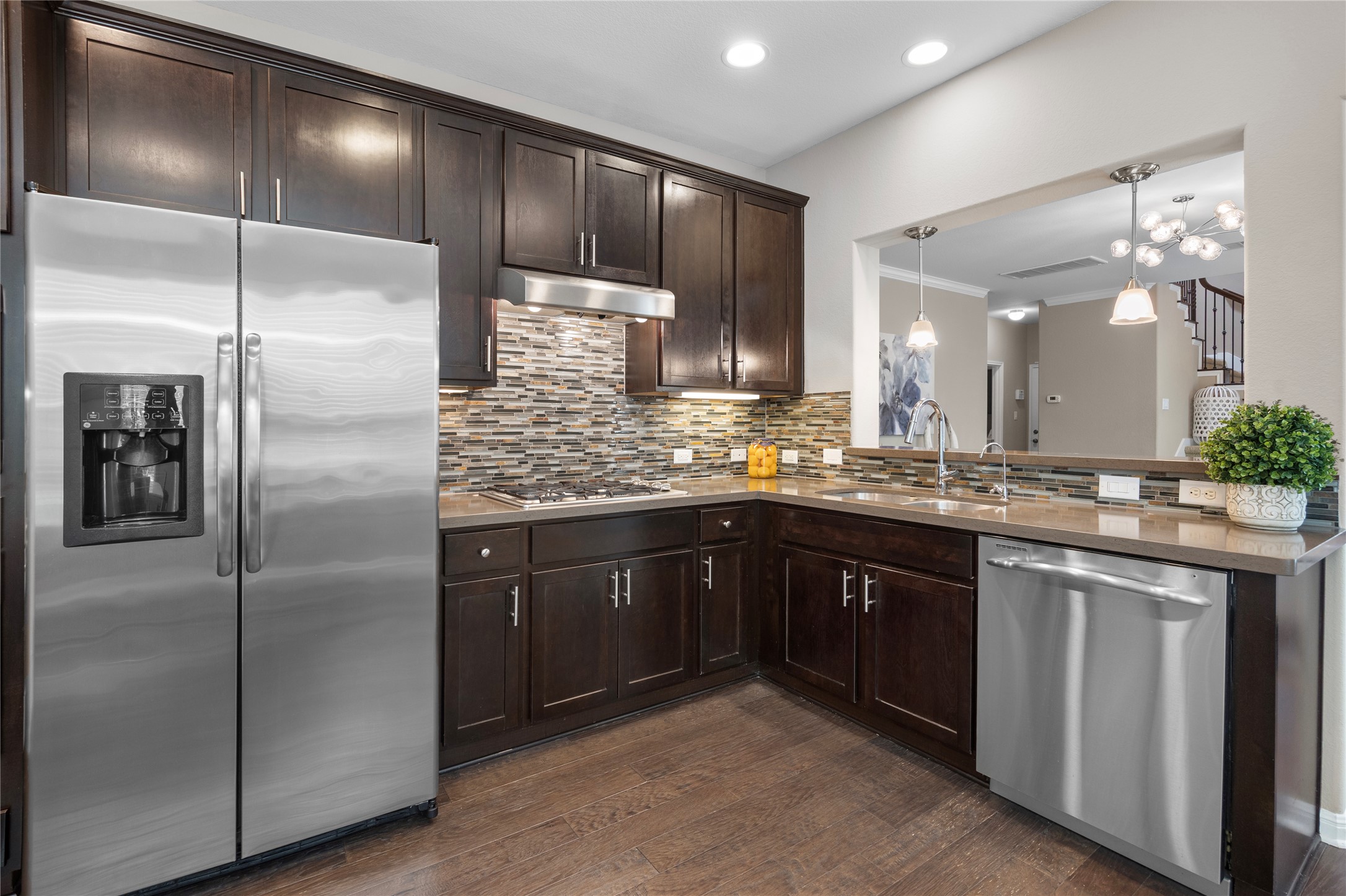7308 Bandera Ranch Trail, Unit A Austin, TX 78750 - Photo 8 of 27 The kitchen features dark wood cabinetry, stainless steel appliances, a mosaic tile backsplash, and recessed lighting