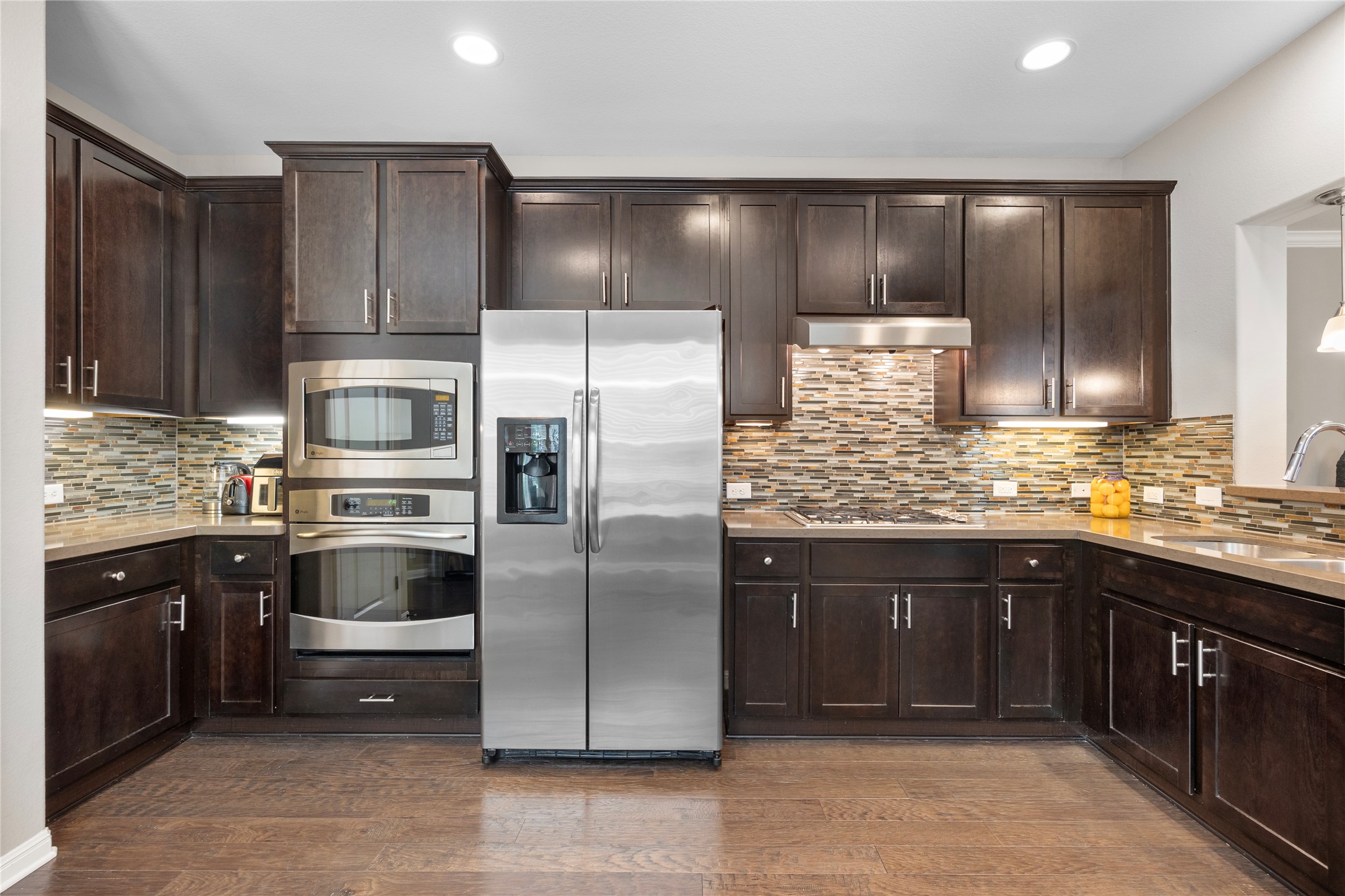 7308 Bandera Ranch Trail, Unit A Austin, TX 78750 - Photo 9 of 27 The kitchen features dark wood cabinetry, stainless steel appliances, and a mosaic tile backsplash
