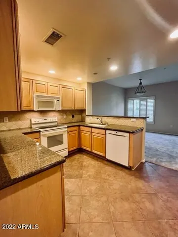 a large kitchen with stainless steel appliances granite countertop a stove a sink dishwasher and a refrigerator