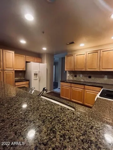 a kitchen with stainless steel appliances granite countertop a stove a sink and a refrigerator