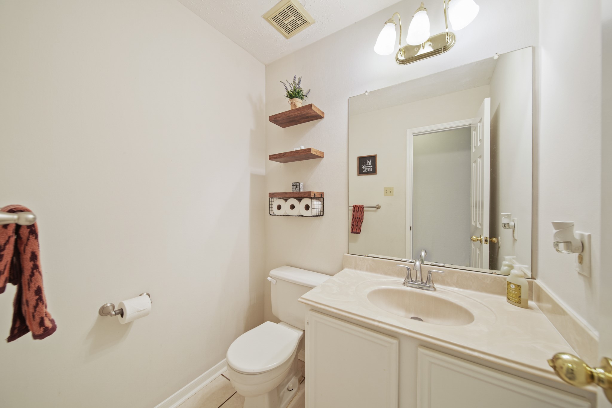 16114 Kintyre Point Road Houston, TX 77095 - Photo 30 of 44 This bathroom features a clean, modern design with a white vanity and sink, a large mirror, and overhead lighting. It includes a toilet, open shelving for storage, and neutral walls, creating a bright and inviting space.