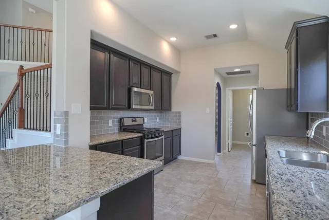 a kitchen with stainless steel appliances granite countertop a sink stove and refrigerator