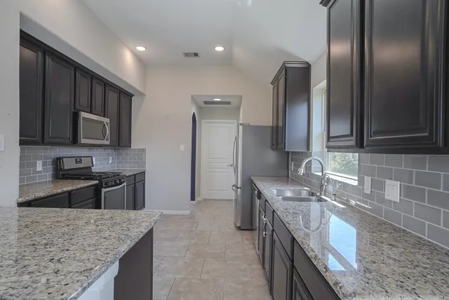 a kitchen with stainless steel appliances granite countertop cabinets sink and window
