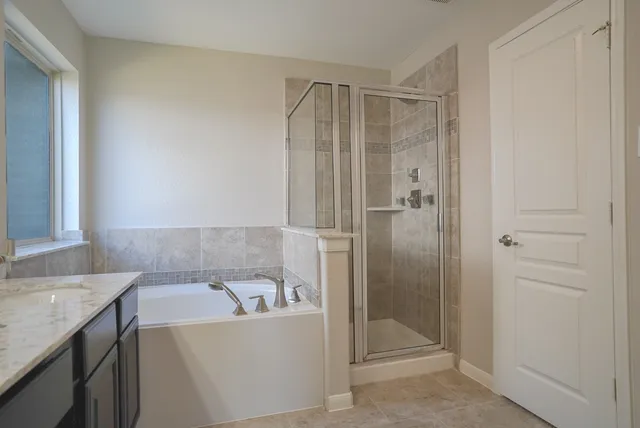 a bathroom with a granite countertop sink a large mirror and a bathtub