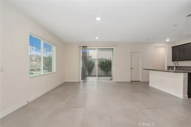 a view of an empty room with a window and a kitchen