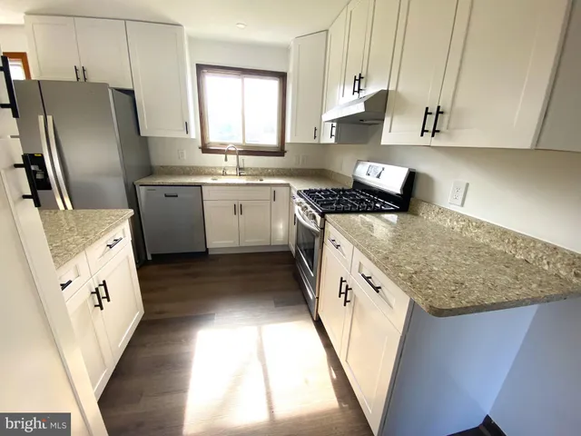 a kitchen with granite countertop a sink a stove and refrigerator