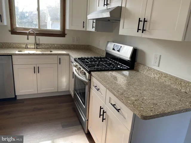 a kitchen with granite countertop a sink stove and cabinets