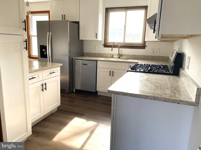 a kitchen with granite countertop a sink stove and refrigerator