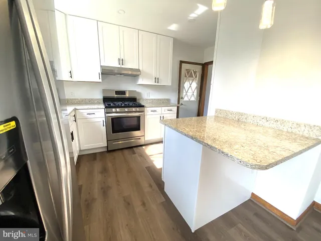 a view of living room with a refrigerator and wooden floor