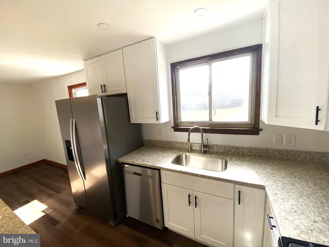 a kitchen with stainless steel appliances wooden floor sink stove and cabinets