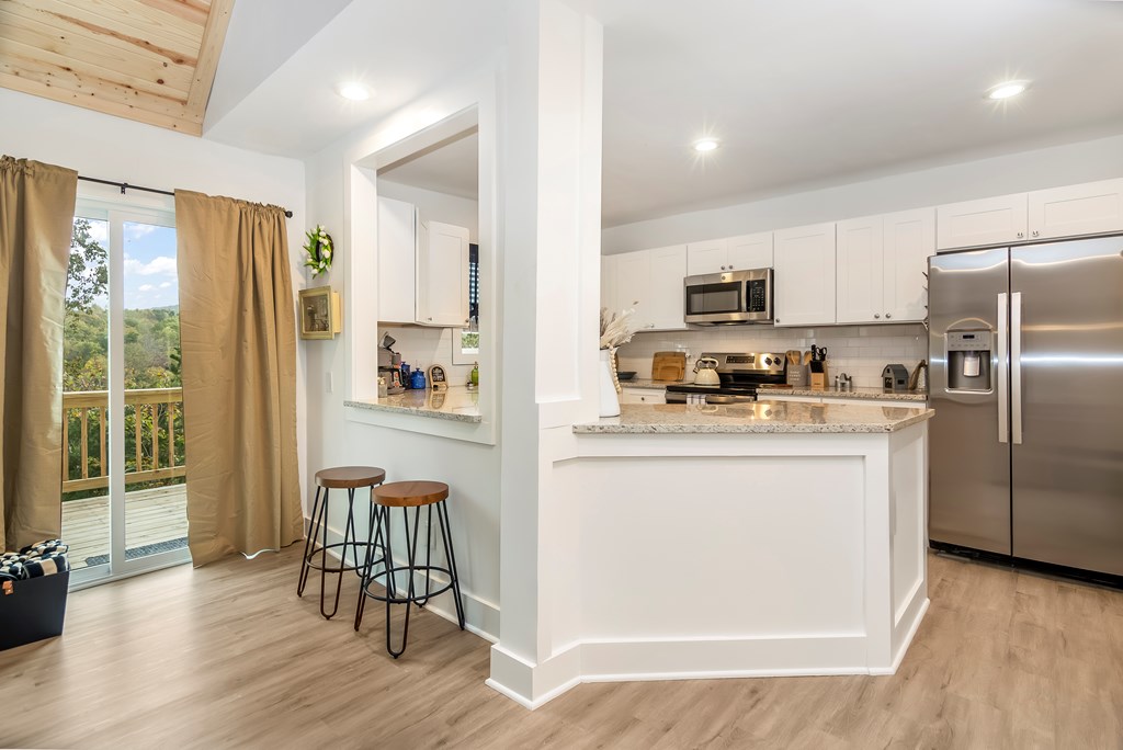 587 Oak Trace East Jasper, GA 30143 - Photo 18 of 47 a kitchen with a refrigerator a microwave a stove and a dining table with wooden floor
