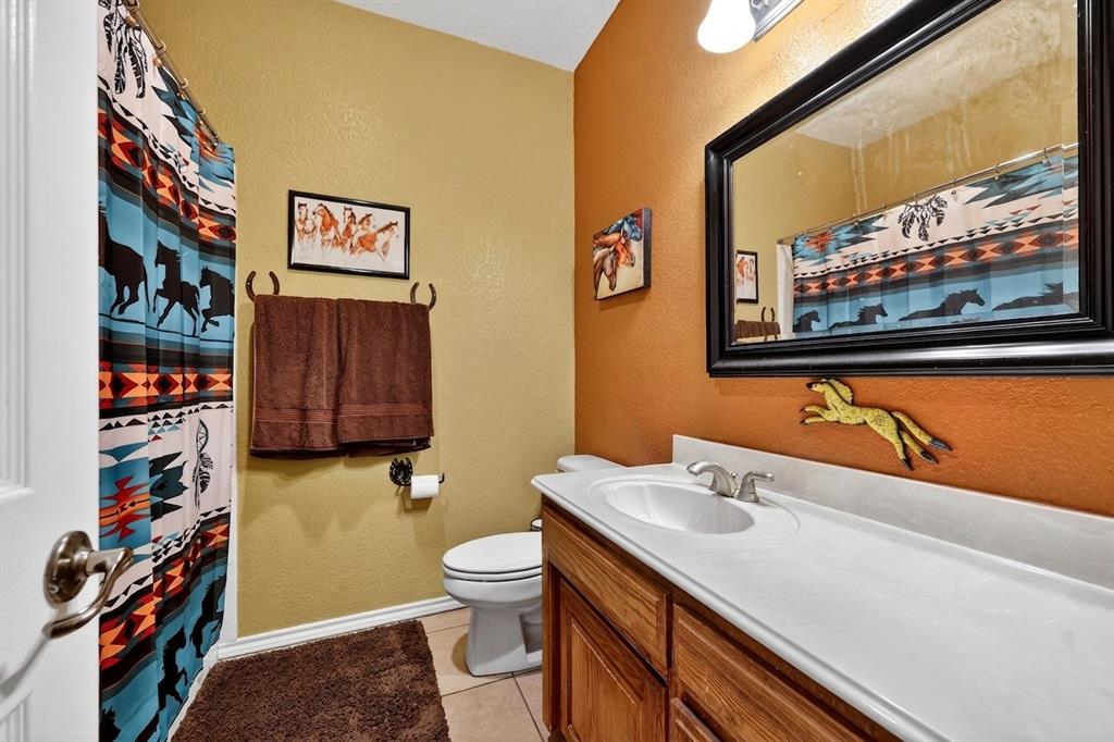 1035 Highland Road Cleburne, TX 76033 - Photo 22 of 36 a bathroom with a sink a toilet and a shower curtain
