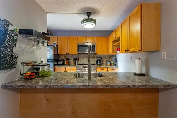 a kitchen with stainless steel appliances granite countertop a sink a stove cabinets counter space and a window