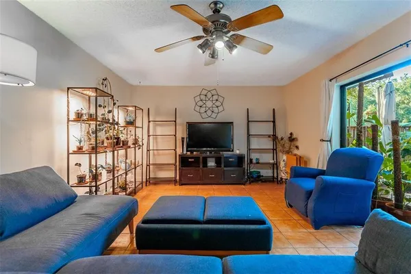 a living room with furniture a flat screen tv and a floor to ceiling window