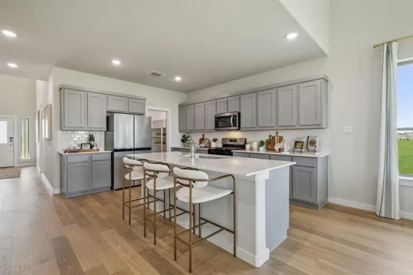 a kitchen with stainless steel appliances granite countertop a refrigerator a stove top oven a sink dishwasher and white cabinets with wooden floor