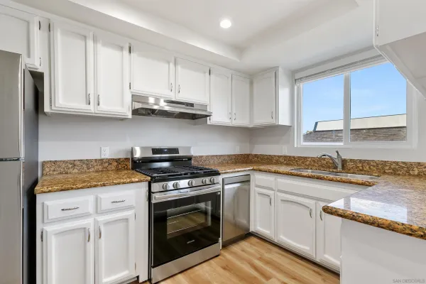 a white kitchen with granite countertop stainless steel appliances