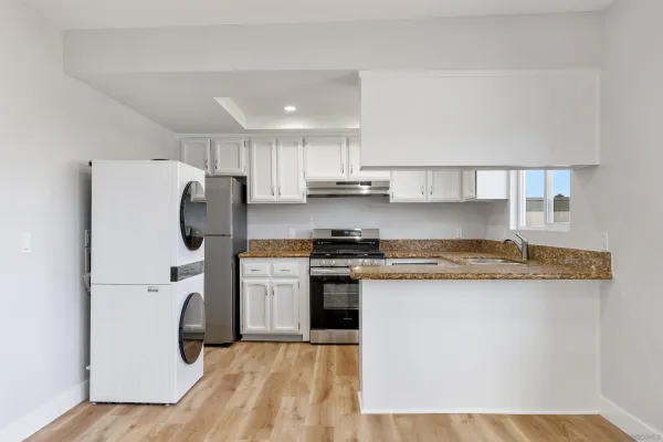 a kitchen with stainless steel appliances granite countertop a refrigerator a stove and a sink