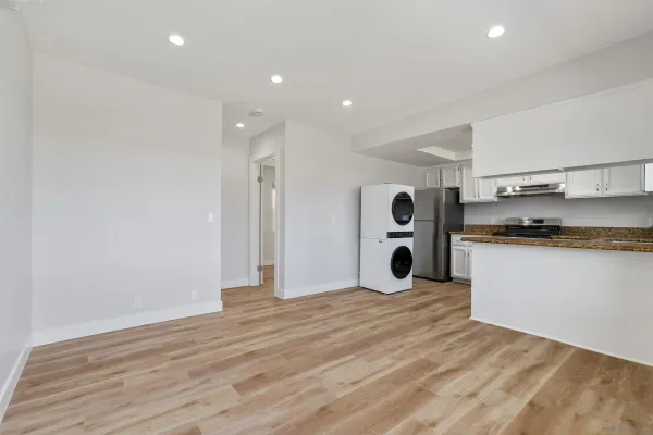 a view of kitchen and empty room with wooden floor