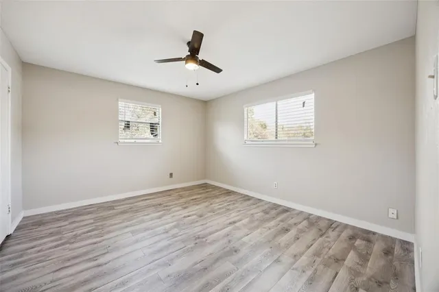 a view of empty room with wooden floor and fan