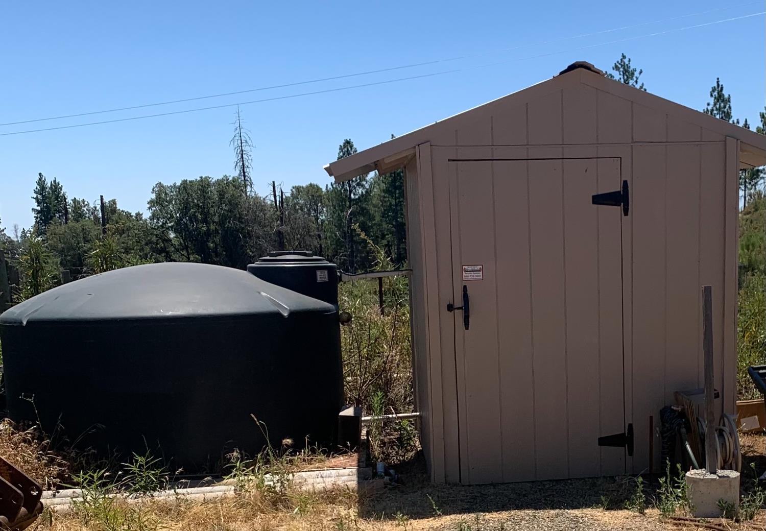 17958 Creations Way Mountain Ranch, CA 95245 - Photo 17 of 28 Upper well pumphouse/storage shed and 1200-gallon storage tank with firehouse fittings in place.