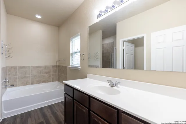 a bathroom with a sink double vanity granite tub shower and a mirror