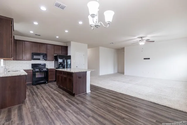 a kitchen with stainless steel appliances granite countertop a sink dishwasher a stove and a refrigerator with wooden floor