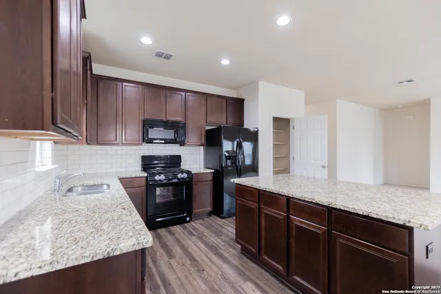 a kitchen with granite countertop stainless steel appliances and wooden cabinets