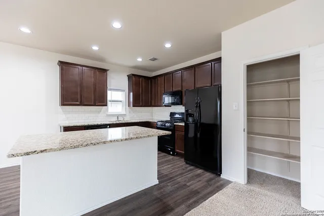 a kitchen with granite countertop a refrigerator and a stove top oven