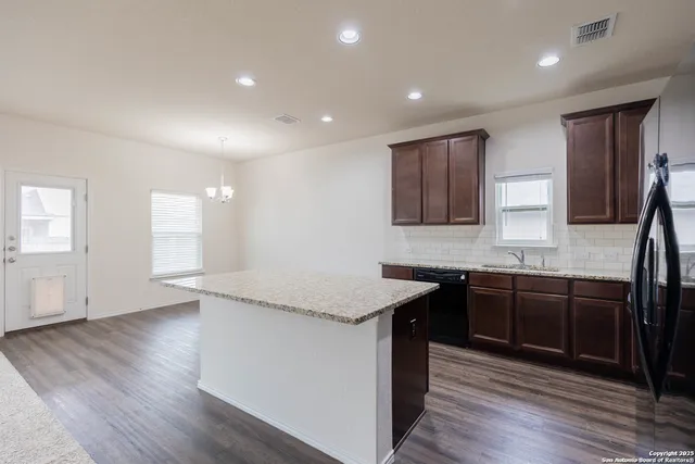 a kitchen with stainless steel appliances granite countertop wooden cabinets a stove top oven and sink