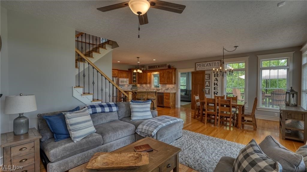 66333 Read Road Cambridge, OH 43725 - Photo 22 of 49 Living room with ceiling fan with notable chandelier, a textured ceiling, and light hardwood / wood-style flooring