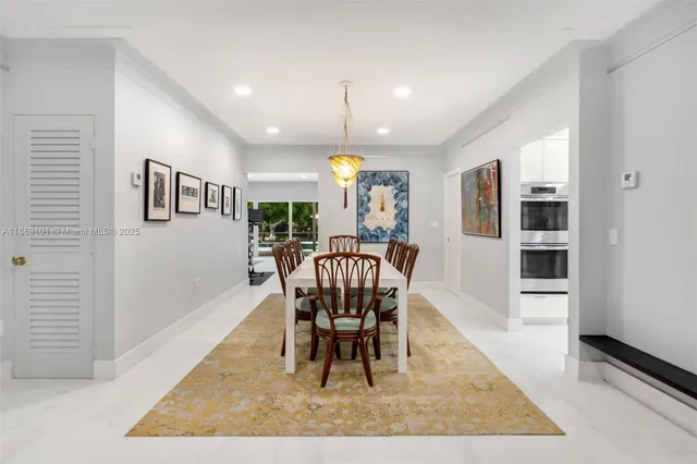 a dining room with wooden floor a chandelier a wooden table and chairs
