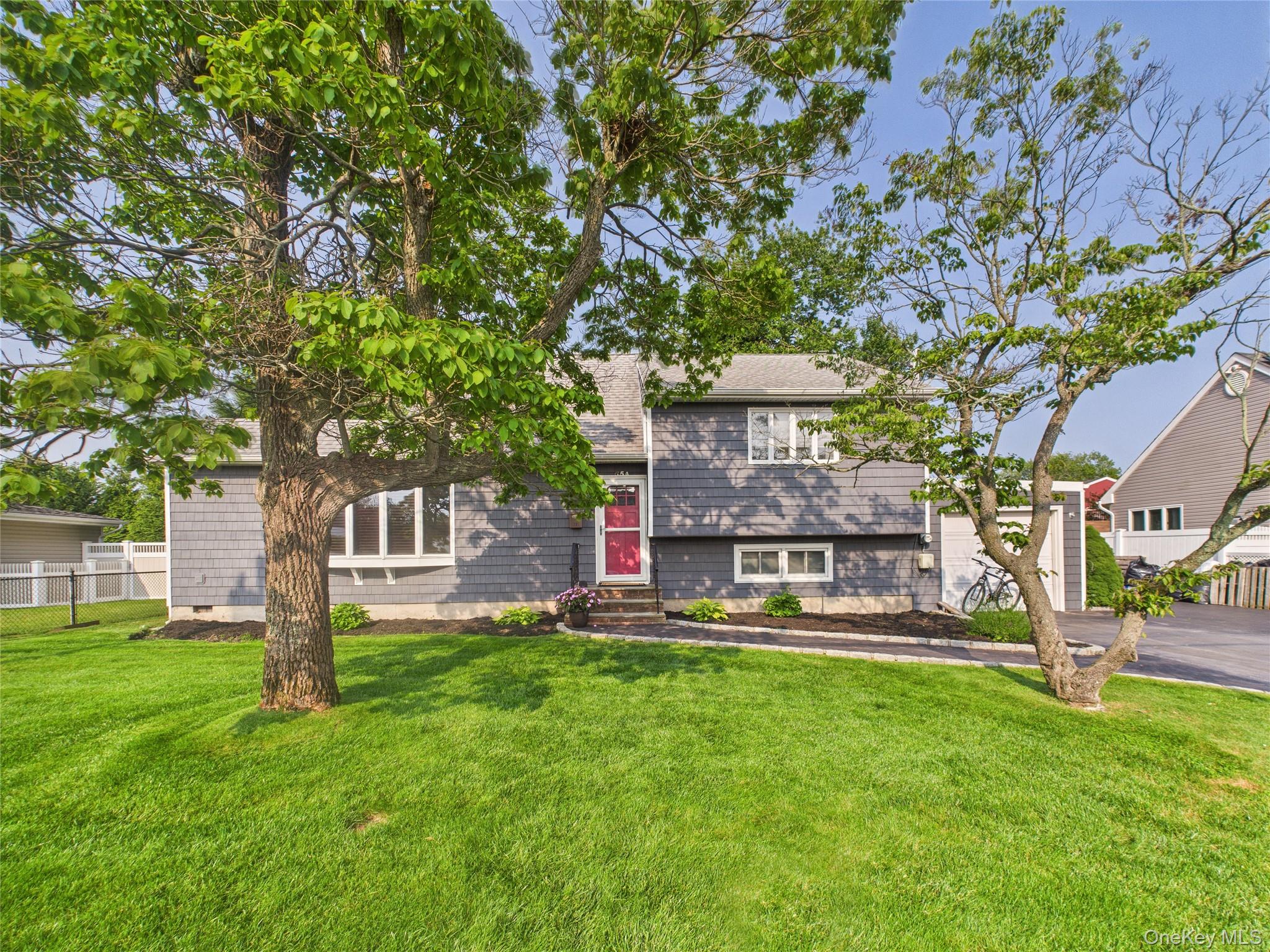 Tri-level home featuring a garage, driveway, and a shingled roof