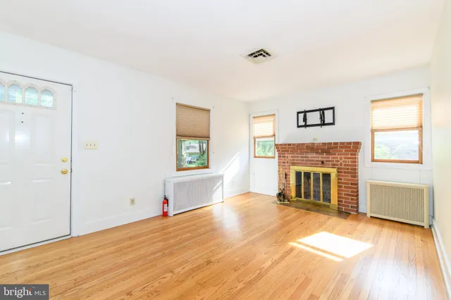 a view of a livingroom with a fireplace window and wooden floor