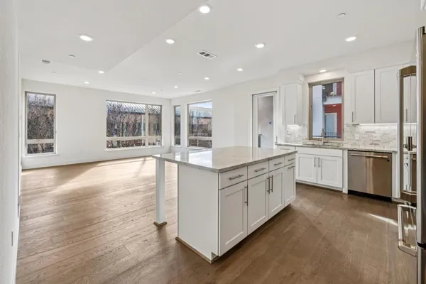 a large kitchen with stainless steel appliances granite countertop a large counter top and a wooden floors