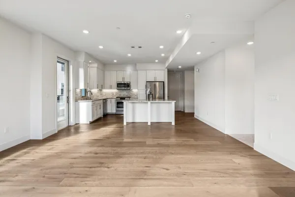 a large white kitchen with granite countertop a stove a sink a window and white cabinets