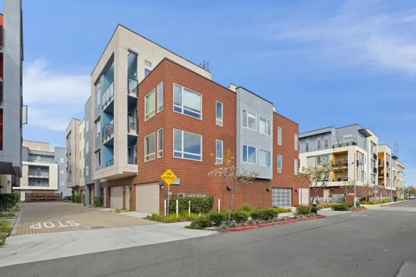a front view of a multi story residential apartment building with yard and bench