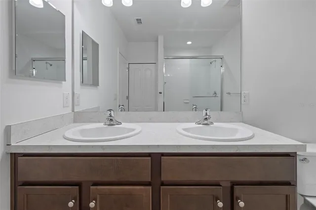 a bathroom with a sink a toilet a mirror and shower