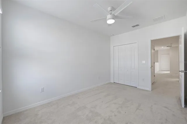 an empty room with a window and ceiling fan