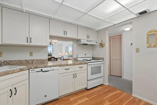 a kitchen with granite countertop white cabinets and white appliances