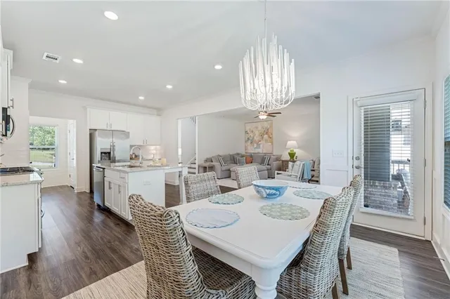 a kitchen with stainless steel appliances kitchen island granite countertop a dining table chairs and stove top oven with wooden floor