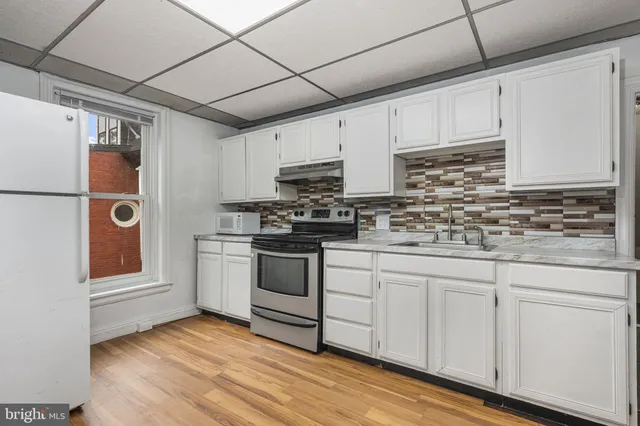 a kitchen with granite countertop white cabinets and white appliances