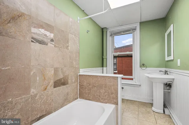 a bathroom with a tub sink and mirror