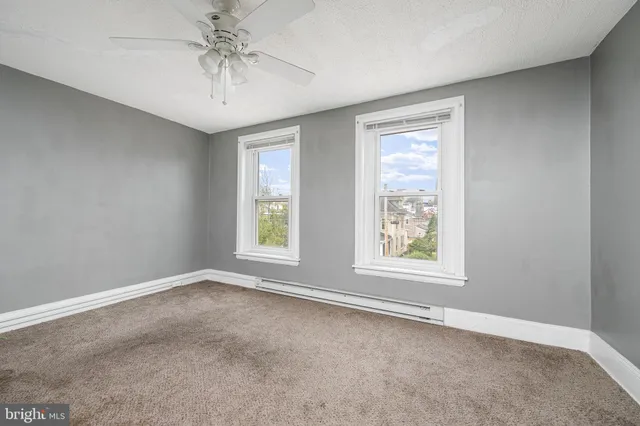 an empty room with windows and chandelier fan