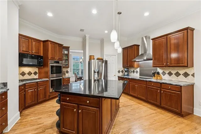 a kitchen with stainless steel appliances granite countertop wooden cabinets a refrigerator a stove a sink and dishwasher with wooden floor