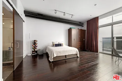 a spacious bedroom with a bed and wooden floor