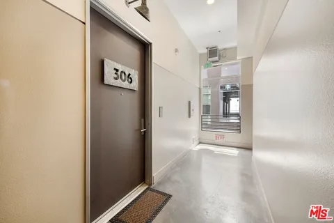 a view of a hallway with wooden floor and a bathroom