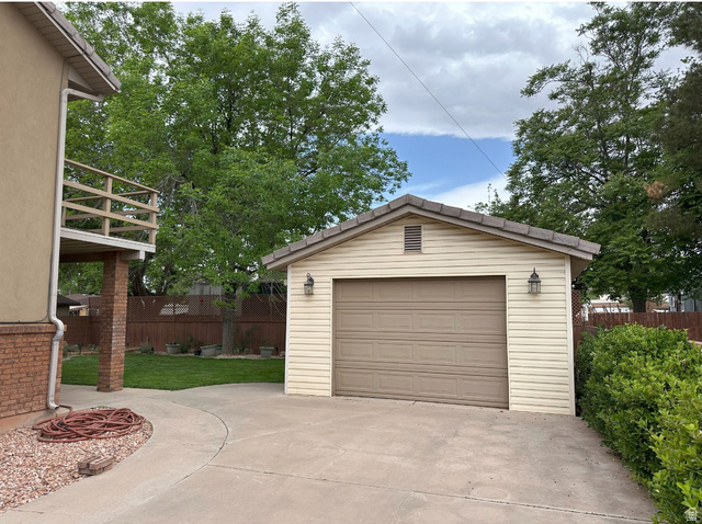 892 Cambridge Drive St. George, UT 84770 - Photo 2 of 65 Detached garage with tan siding, a brown garage door, and decorative exterior lighting