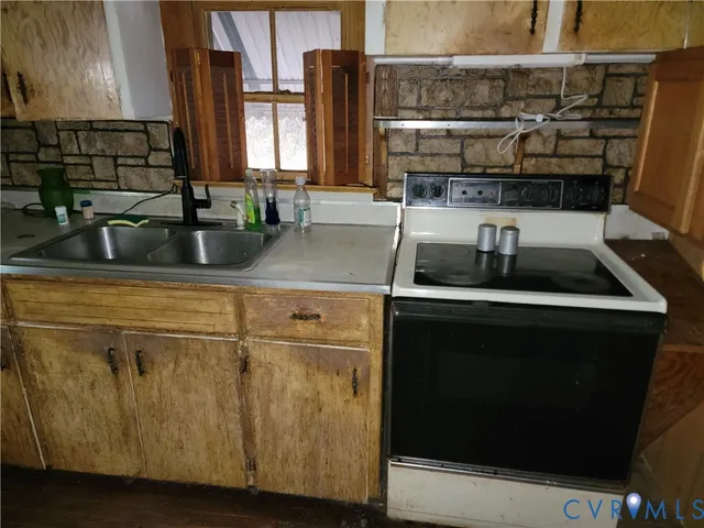 a kitchen with a sink and a stove top oven with wooden floor